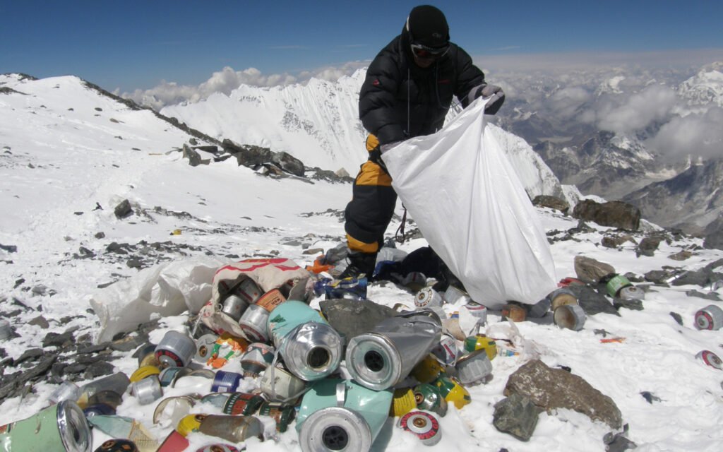 Déchets abandonnés sur les flancs de l'Everest — bouteilles d'oxygène usagées et tentes déchirées — illustrant le bilan environnemental d'un siècle d'alpinisme commercial.