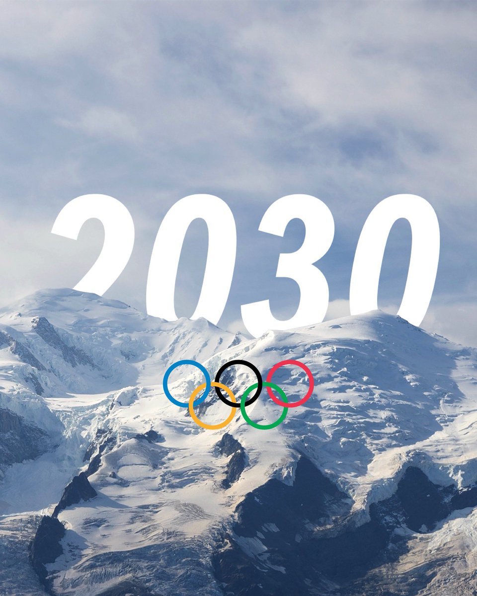 Anneaux olympiques sur fond de montagne enneigée avec grues de construction en arrière-plan, illustrant les enjeux économiques des JO d'hiver 2030 dans les Alpes françaises