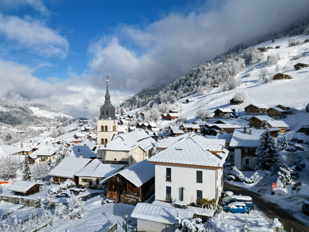 Skieurs sur une piste damée entourée de chalets d'alpage savoyards authentiques dans la station d'Arêches-Beaufort, réputée pour son enneigement et sa tranquillité.
