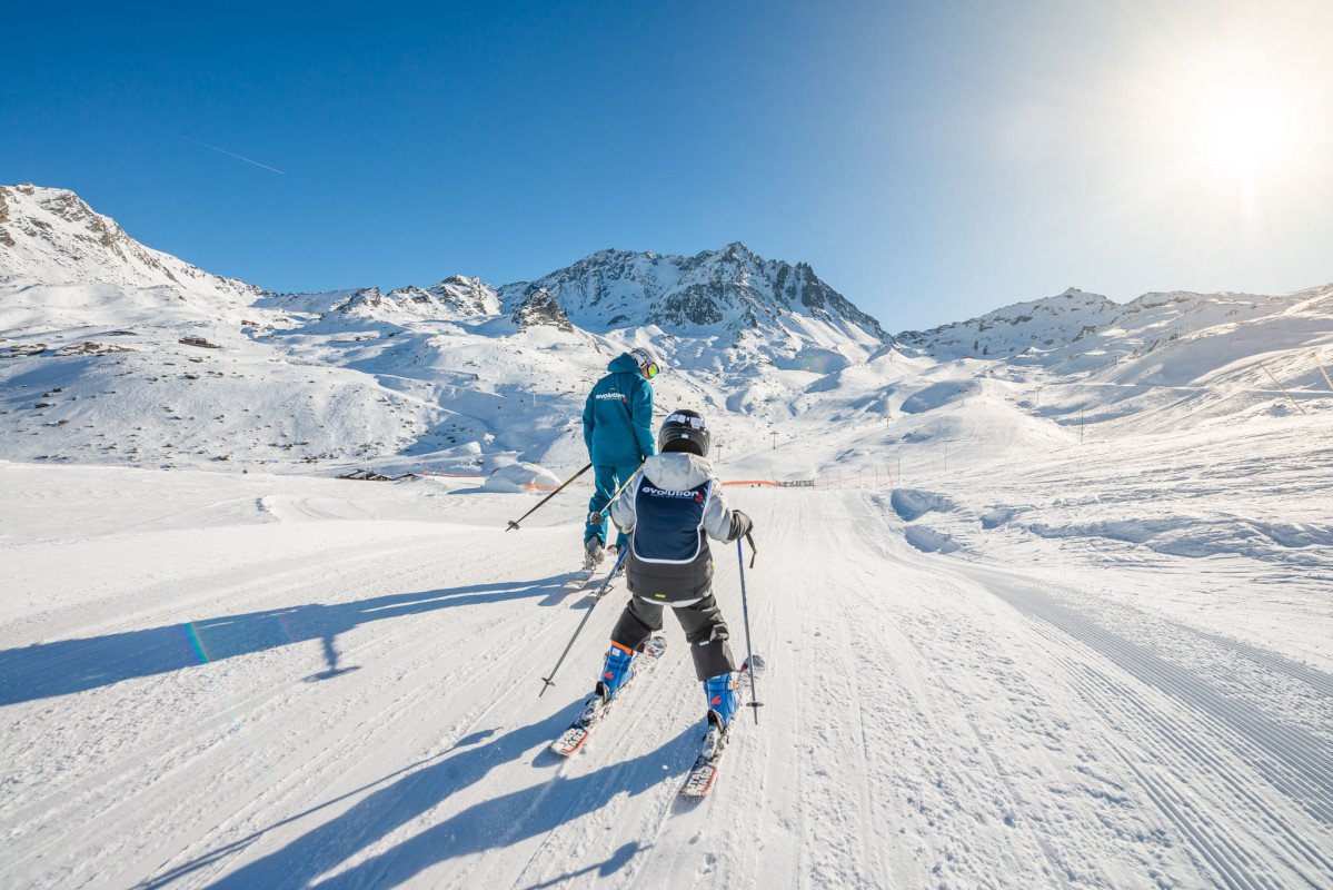 Skieur descendant une piste parfaitement damée sous un grand soleil printanier dans la station de Val Thorens, la plus haute d'Europe.
