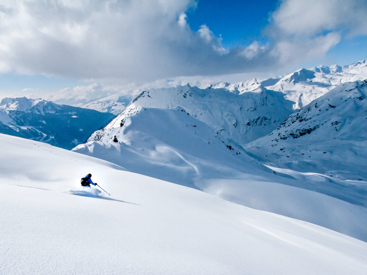 Skieur descendant une pente couverte de poudreuse fraîche entre les sapins dans la station confidentielle de Sainte-Foy-Tarentaise dans les Alpes.