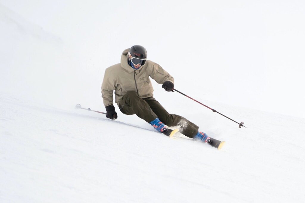 Trace parfaite de carving sur une piste damée, démontrant l'effet du rayon de courbure et du cambre du ski.