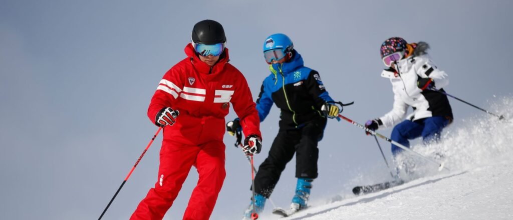 Groupe de skieurs alignés sur une piste lors d'une leçon d'apprentissage, illustrant la transmission technique en école de ski.