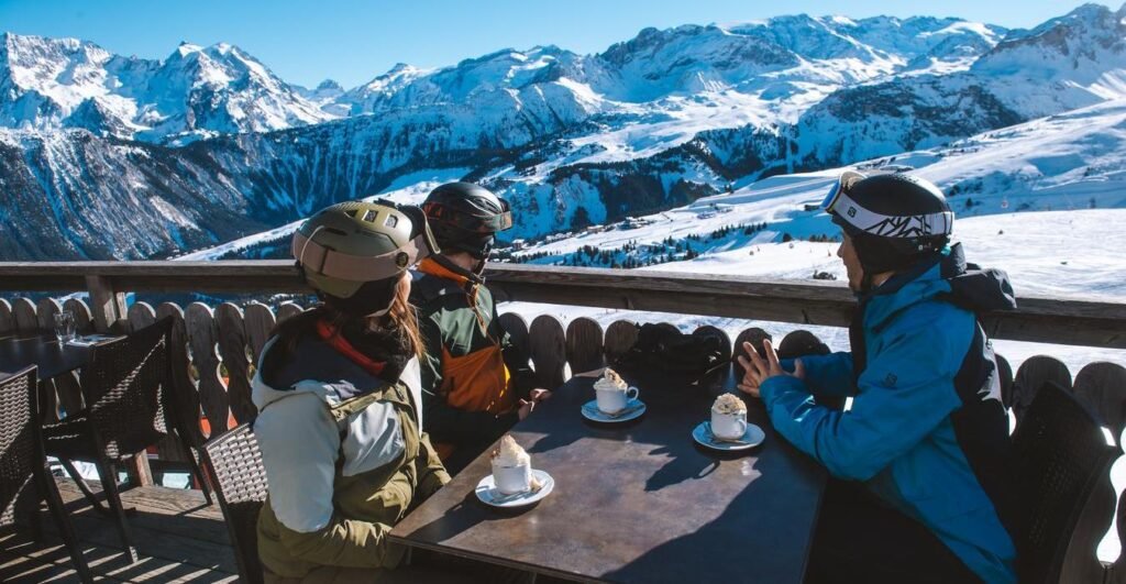 Skieurs déjeunant en plein soleil sur la terrasse d'un restaurant d'altitude, le moment où la peau est la plus exposée aux brûlures.