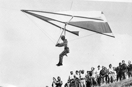 L'envol spectaculaire d'un deltaplane rudimentaire depuis un sommet enneigé, illustrant les débuts du vol libre en très haute altitude.