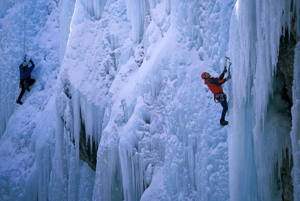 Gros plan sur un alpiniste gravissant une cascade de glace verticale à l'aide de piolets-traction d'époque, symbole de l'engagement extrême.