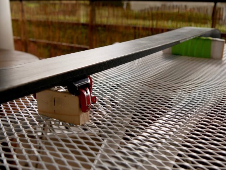 Ski bloqué dans un étau professionnel d'atelier, prêt à recevoir un affûtage des carres et un fartage à chaud.