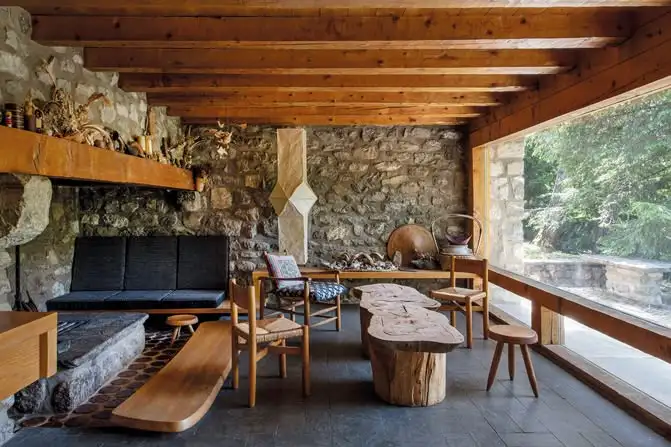 Intérieur d'un appartement de montagne au design minimaliste et fonctionnel, habillé de bois clair, avec de grandes baies vitrées ouvertes sur la nature.