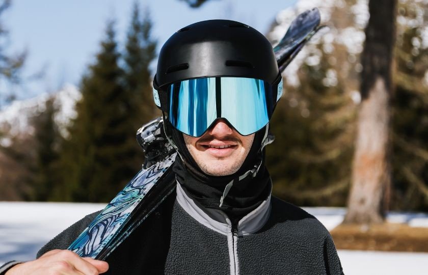 Gros plan sur le reflet des sommets enneigés dans l'écran miroir d'un masque de ski haut de gamme par grand soleil.