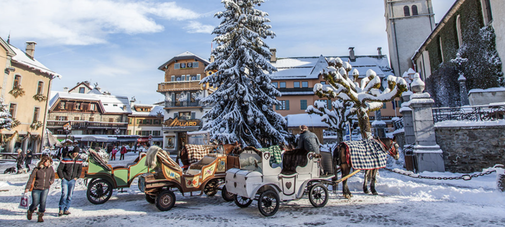 Place centrale du village de Megève illuminée la nuit sous la neige, avec une calèche traditionnelle tirée par des chevaux