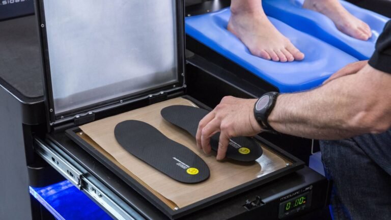 Pied posé sur un outil de mesure biomécanique dans un atelier spécialisé, première étape cruciale du bootfitting pour chaussures de ski.