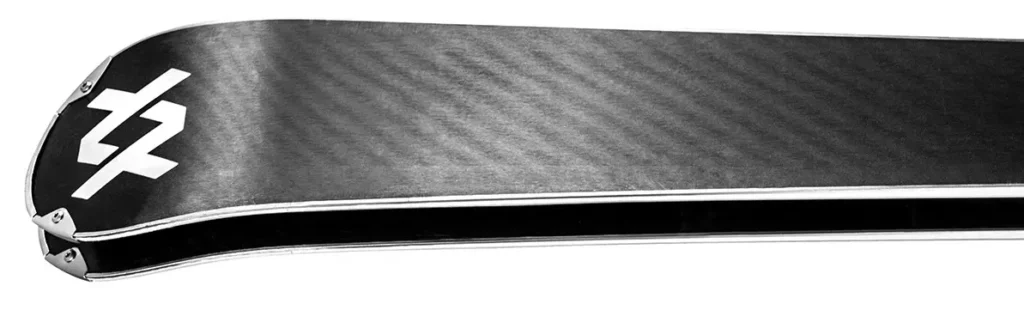 Gros plan sur la semelle d'un ski glissant sur les cristaux de neige, illustrant l'importance de l'imprégnation de fart dans le polyéthylène.