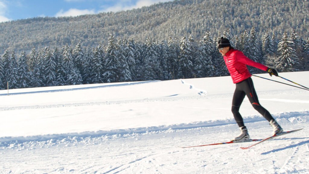 Skieur pratiquant le skating avec intensité sur un large plateau blanc, illustrant l'aspect sportif et cardio de la discipline.