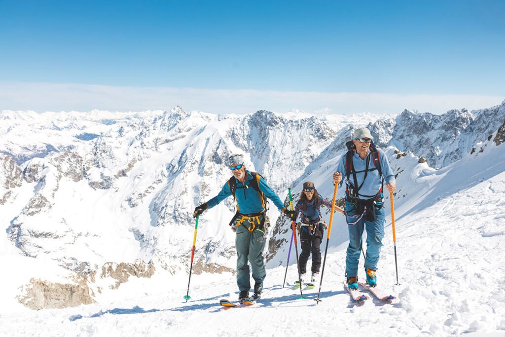 Des skieurs de randonnée en plein effort, progressant sur des pentes raides à l'aube, les peaux de phoque accrochant la neige dure.