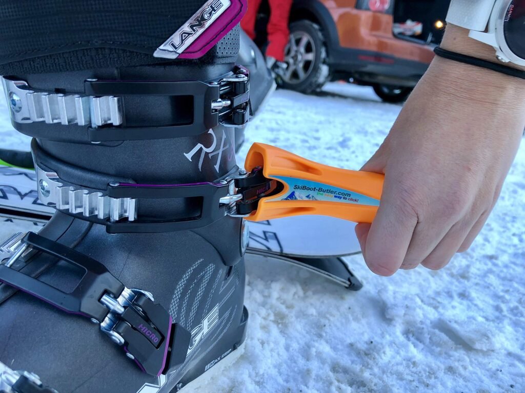 Skieur ajustant avec précision les boucles de ses chaussures de ski alpin sur la neige, recherchant le maintien parfait sans douleur.