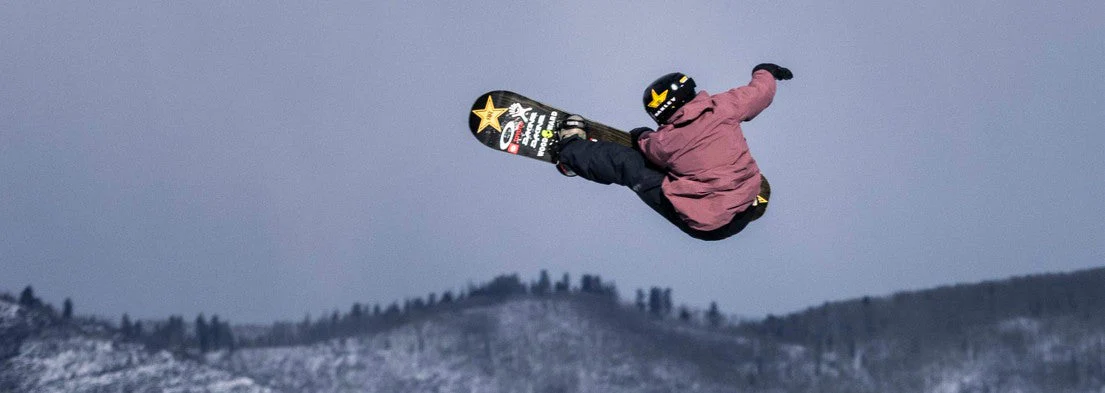 Snowboarder réalisant un saut en attrapant sa planche (grab), symbole de la culture freestyle et rebelle apparue dans les années 90.