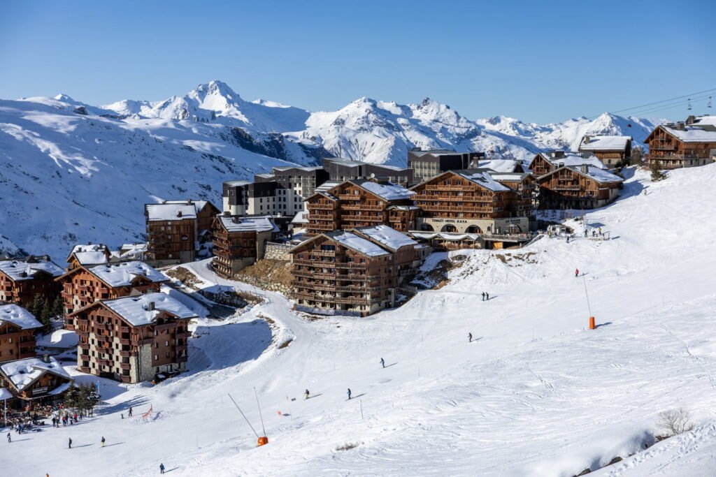 Quelques skieurs profitant tranquillement d'un immense domaine skiable sous un ciel bleu, loin de la cohue des vacances scolaires.