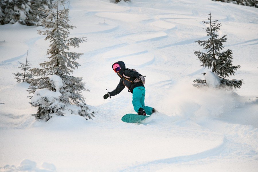 Surfeur des neiges traçant une grande courbe dans la poudreuse vierge, illustrant la recherche de liberté des pionniers de la discipline.