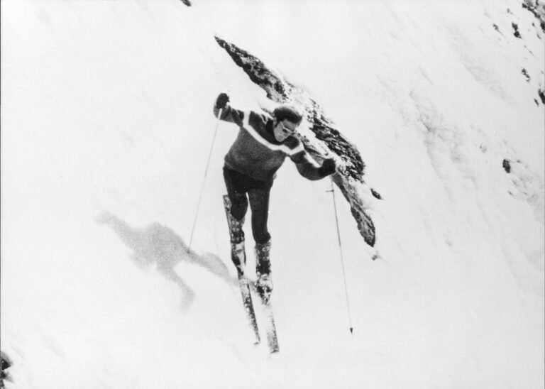 Skieur des années 70 penché au-dessus du vide avant de s'engager dans une pente d'une inclinaison terrifiante, illustrant les débuts du ski extrême.