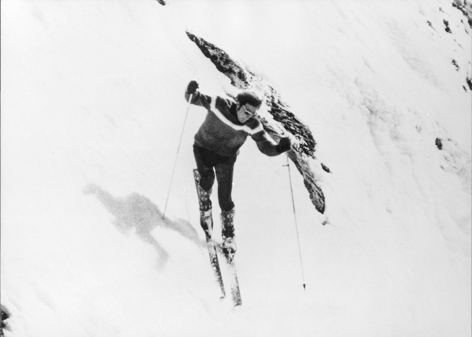 Skieur des années 70 penché au-dessus du vide avant de s'engager dans une pente d'une inclinaison terrifiante, illustrant les débuts du ski extrême.
