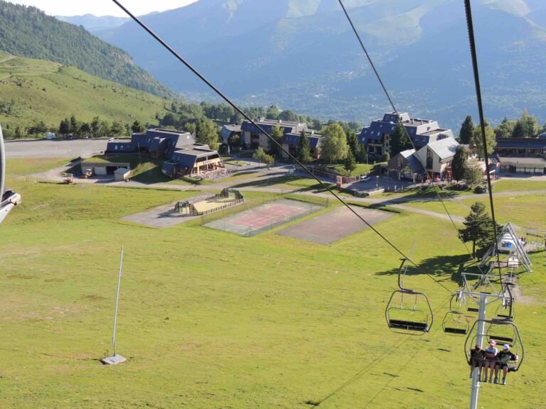 Piste de ski avec très peu de neige entourée de prairies d'herbe sèche, illustrant le manque d'enneigement en basse altitude.