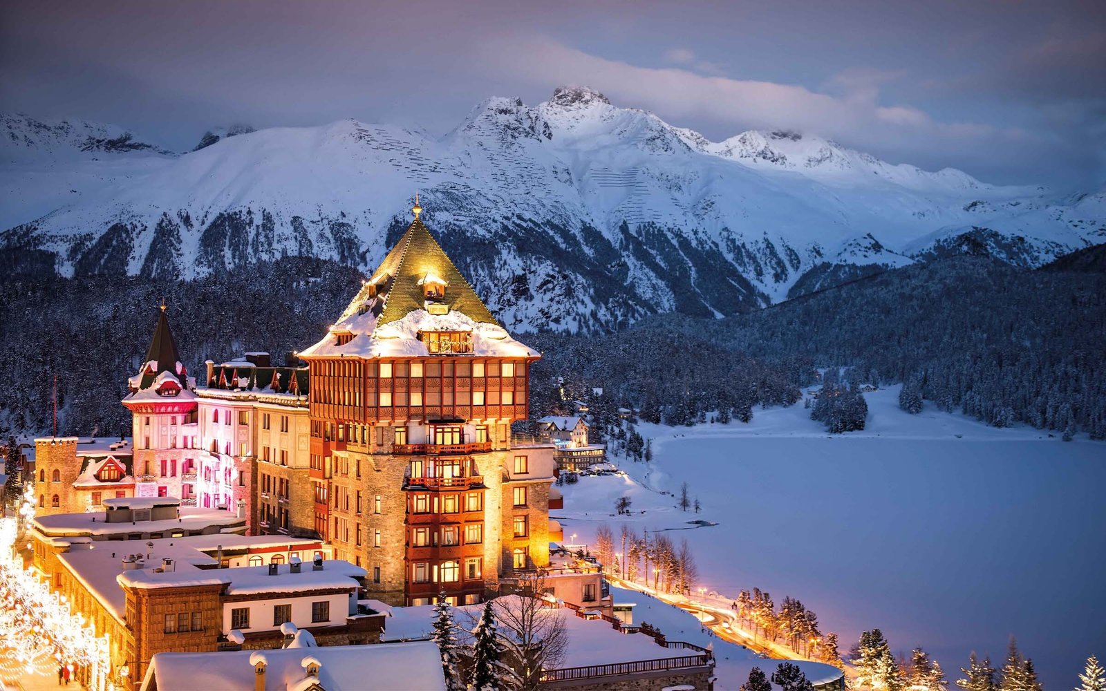 Personnes élégamment vêtues profitant d'une boisson chaude sur la terrasse d'un établissement de luxe enneigé, rappelant les origines britanniques de l'après-ski.