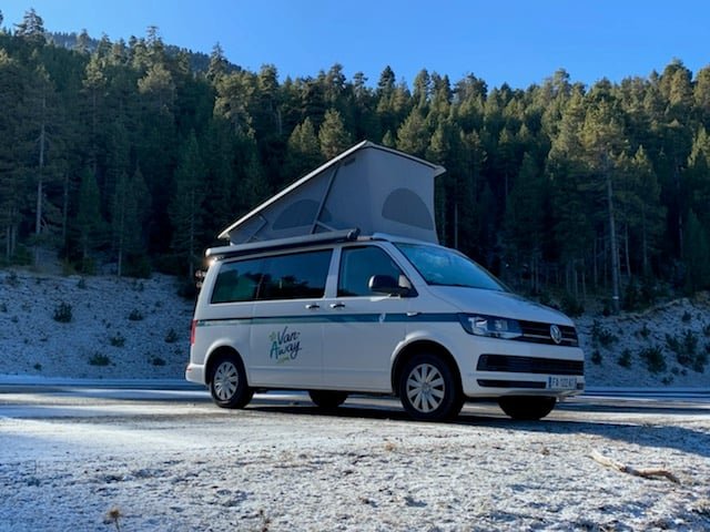 Fourgon aménagé stationné en pleine nature sous une épaisse couche de neige, illustrant le road-trip hivernal extrême.