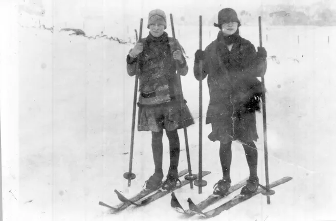 Ancienne paire de skis en bois massif posée dans la neige, témoignant de l'équipement rudimentaire des pionniers de la glisse.