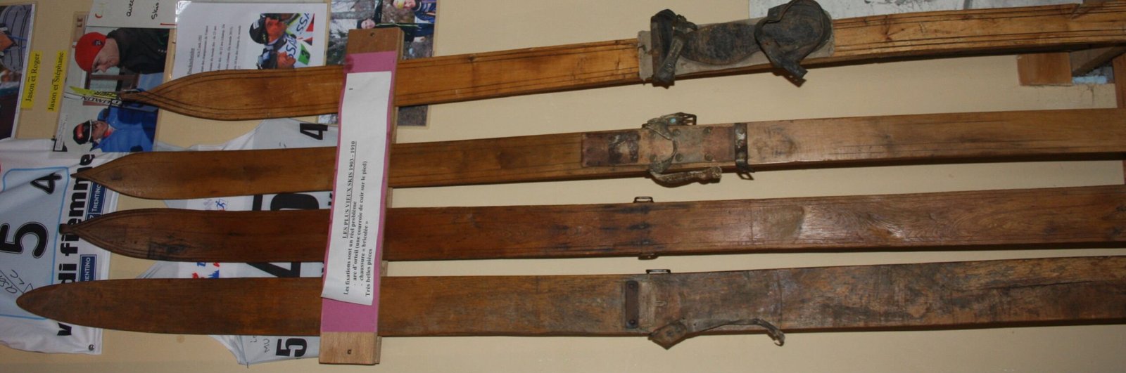 Gros plan sur une paire de vieux skis en bois massif reposant dans la neige, rappelant l'équipement rudimentaire des pionniers de l'alpinisme.