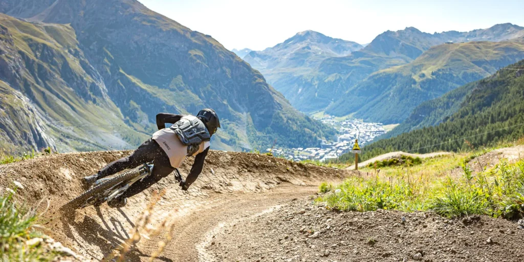 Cycliste pratiquant le VTT de descente sur les sentiers alpins l'été, l'une des activités phares de la diversification des stations.