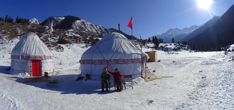 Campement traditionnel de yourtes kirghizes, isolé dans une vallée reculée et lourdement enneigée des monts Tian Shan.