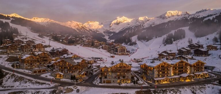 Vue aérienne d'une station alpine haut de gamme au crépuscule illustrant la gentrification progressive du tourisme de montagne français au profit d'une clientèle internationale en 2026