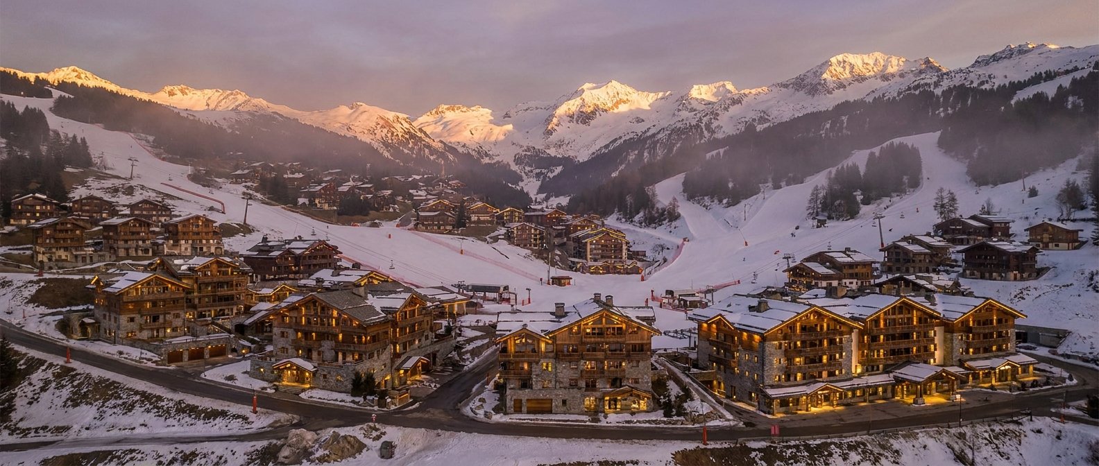 Vue aérienne d'une station alpine haut de gamme au crépuscule illustrant la gentrification progressive du tourisme de montagne français au profit d'une clientèle internationale en 2026