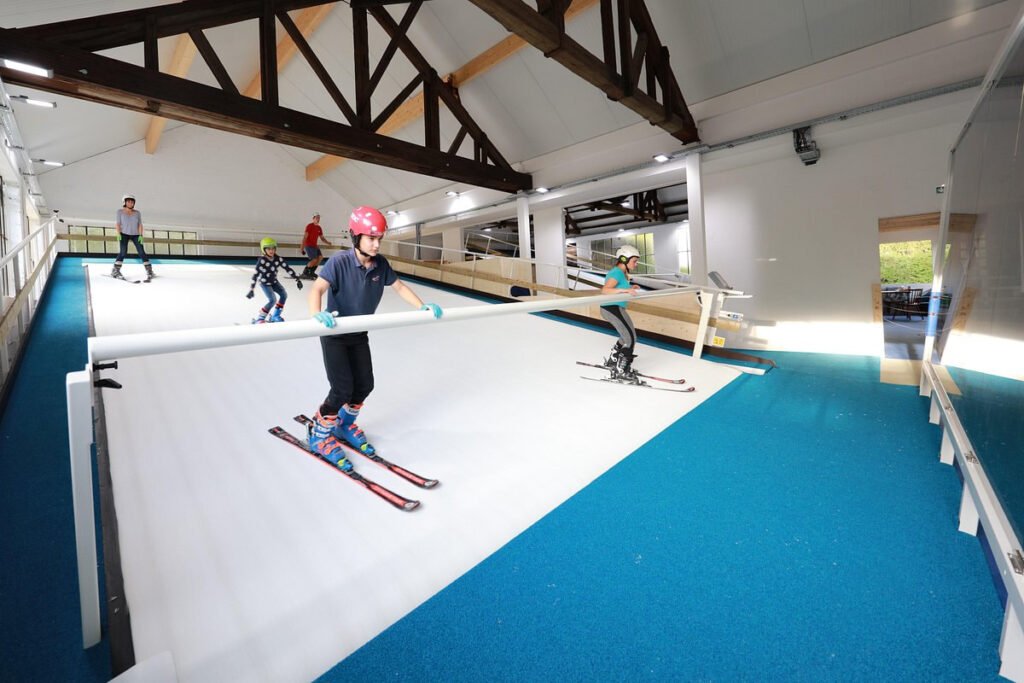 Skieur s'entraînant sur un tapis roulant de ski indoor avec analyse vidéo et coach, complexe de type Ski Indoor 4810 au pied du Mont-Blanc