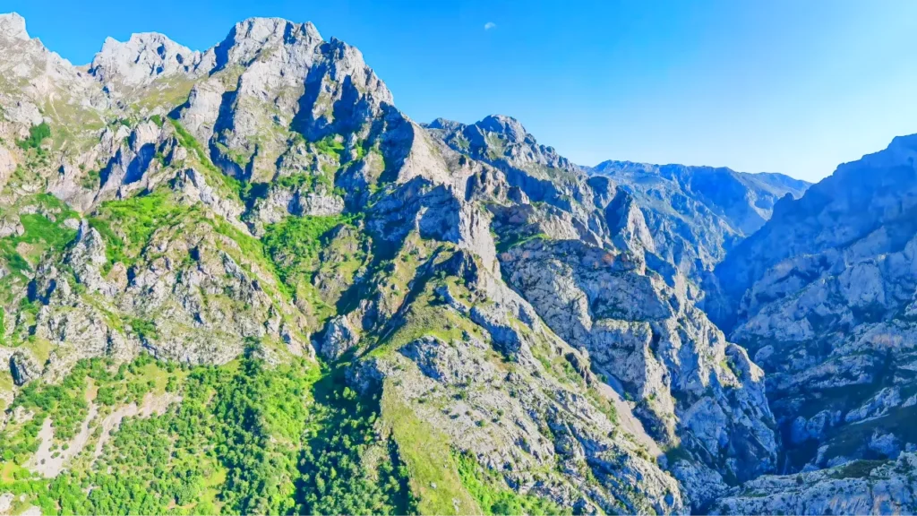 Montagnes rocheuses escarpées et verdoyantes sous un ciel bleu dégagé