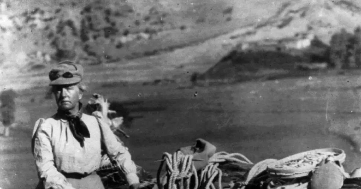 Femme en tenue d'alpiniste avec du matériel devant des montagnes